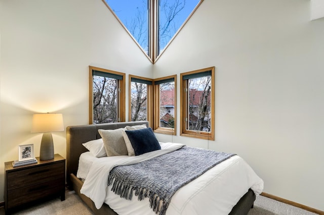 bedroom featuring carpet, a towering ceiling, and baseboards