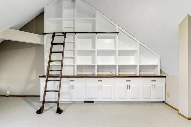 interior space featuring vaulted ceiling, baseboards, and light colored carpet