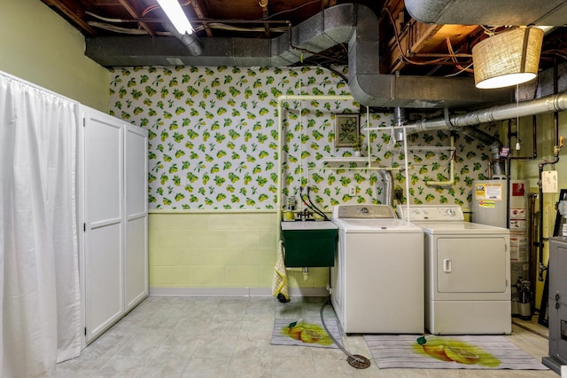 laundry room with a sink, laundry area, gas water heater, and washer and dryer