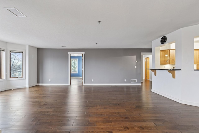 unfurnished room featuring dark wood-style floors, visible vents, and a wealth of natural light