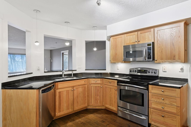 kitchen with dark wood-style floors, dark countertops, appliances with stainless steel finishes, a sink, and a textured ceiling