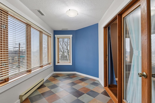 interior space with a textured ceiling, a baseboard radiator, visible vents, baseboards, and tile patterned floors