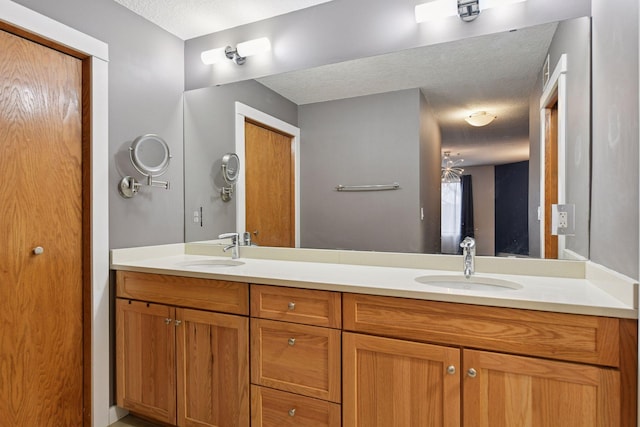 full bathroom with a textured ceiling, double vanity, and a sink