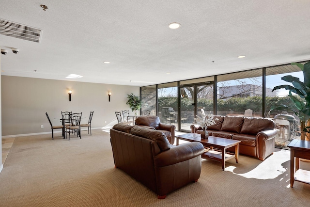 living area with light carpet, plenty of natural light, visible vents, and floor to ceiling windows