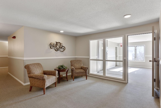 living area featuring a textured ceiling, carpet flooring, and baseboards