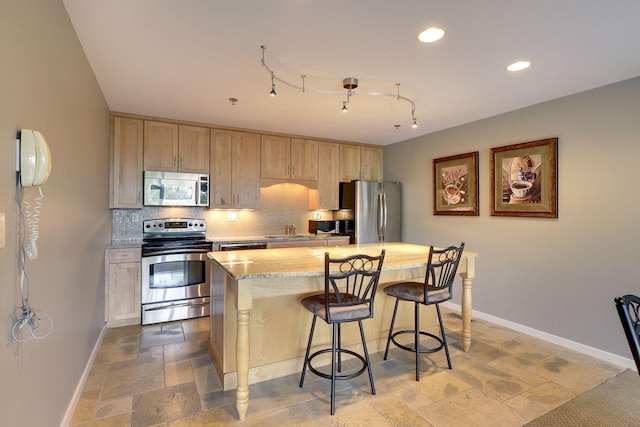 kitchen with stone tile floors, baseboards, decorative backsplash, appliances with stainless steel finishes, and a sink