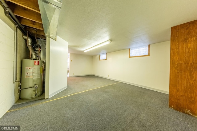 basement featuring water heater, a textured ceiling, carpet, and concrete block wall