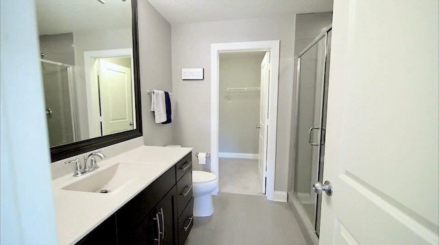 full bathroom with toilet, a stall shower, vanity, and baseboards