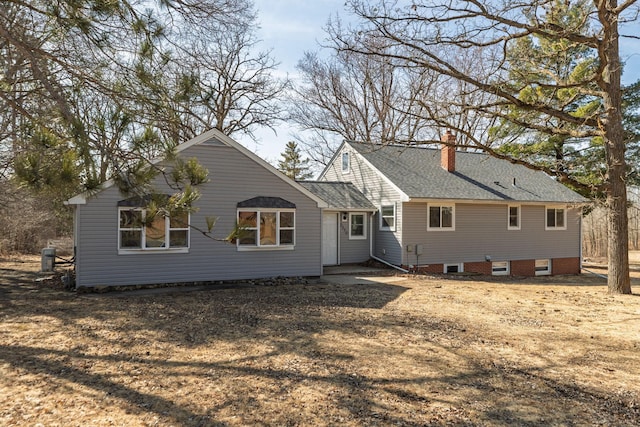 rear view of property featuring a chimney and roof with shingles