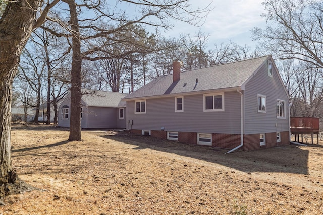 back of house featuring a wooden deck, roof with shingles, and a chimney