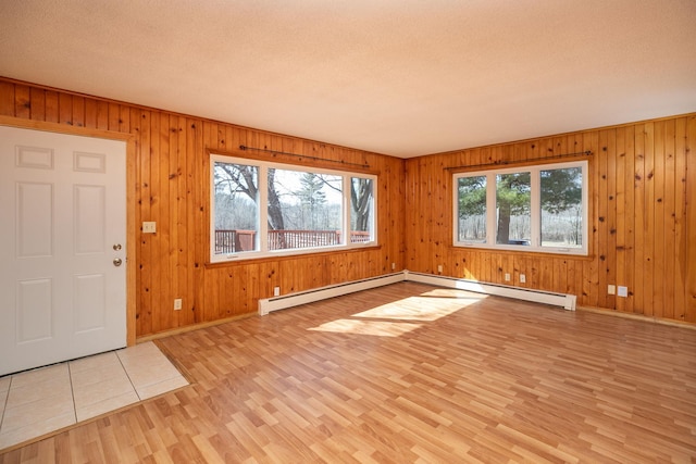 entrance foyer featuring light wood finished floors, baseboard heating, a textured ceiling, and baseboards