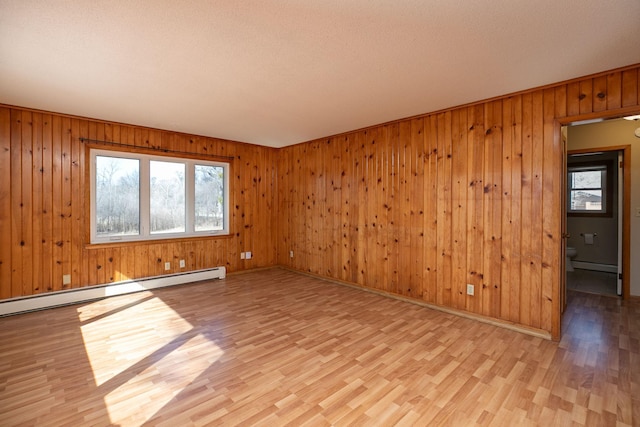 unfurnished room with light wood-style floors, baseboards, and a baseboard radiator