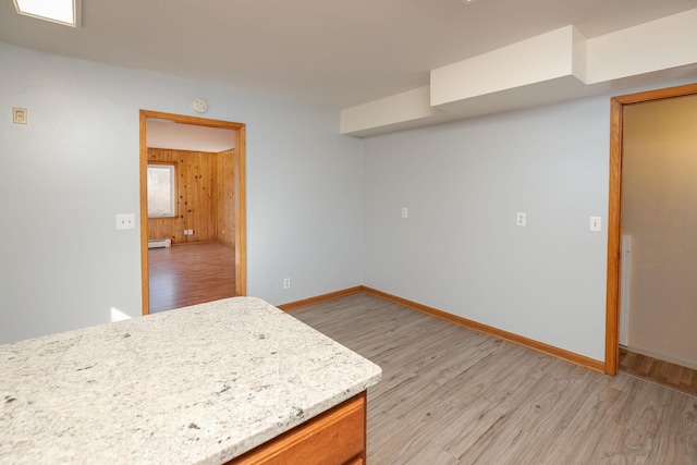 kitchen with baseboard heating, wooden walls, baseboards, and light wood finished floors