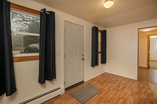 foyer entrance featuring a baseboard heating unit, plenty of natural light, and light wood finished floors