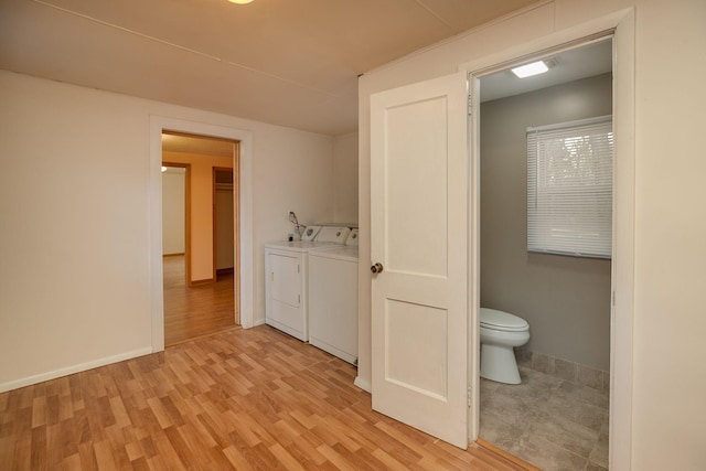 bathroom with washing machine and dryer, toilet, baseboards, and wood finished floors