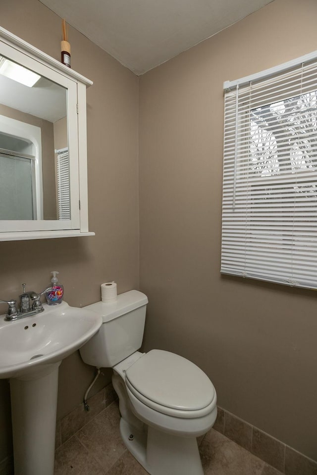 bathroom featuring baseboards, toilet, and tile patterned flooring