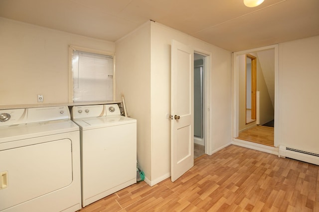 clothes washing area featuring washer and clothes dryer, laundry area, light wood-type flooring, and a baseboard radiator