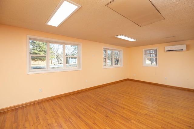 unfurnished room featuring light wood finished floors, a healthy amount of sunlight, and an AC wall unit