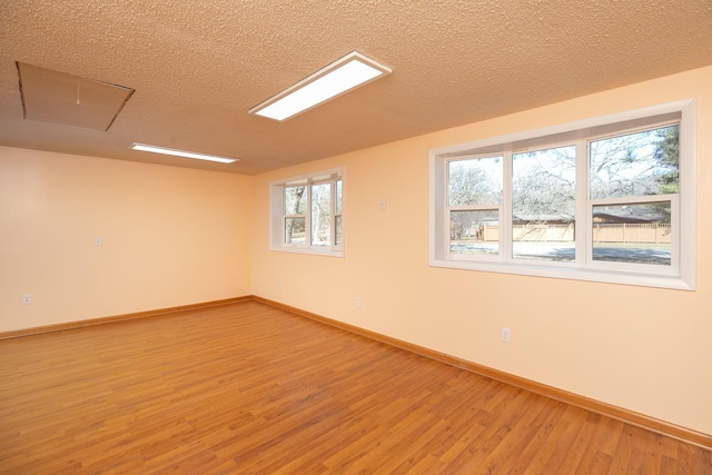 unfurnished room featuring light wood-style flooring, baseboards, and a textured ceiling