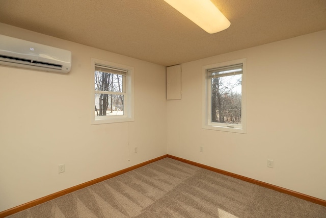 spare room featuring baseboards, carpet, a healthy amount of sunlight, and a wall unit AC