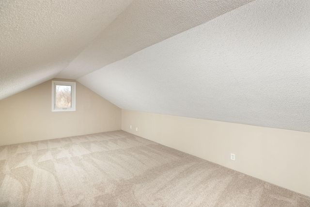 bonus room with a textured ceiling, lofted ceiling, and carpet floors