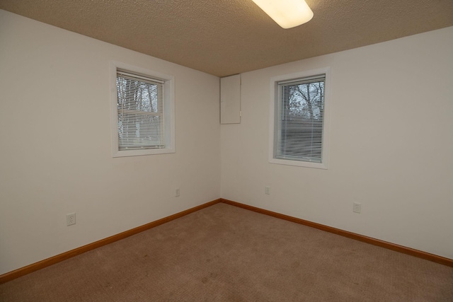 carpeted spare room with a textured ceiling and baseboards