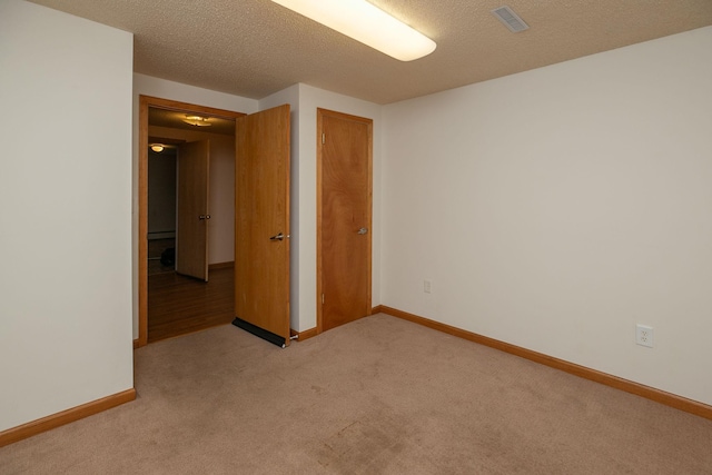 empty room featuring visible vents, baseboards, light colored carpet, and a textured ceiling