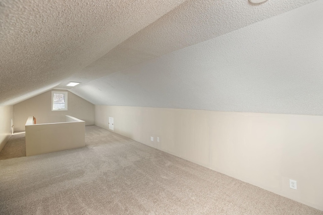 additional living space featuring vaulted ceiling, carpet floors, and a textured ceiling