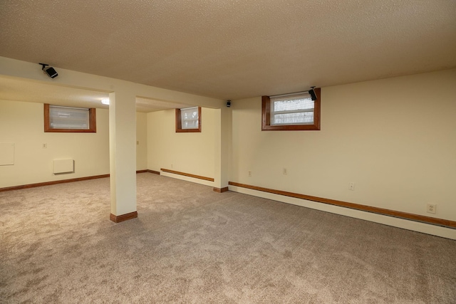 below grade area with a textured ceiling, carpet flooring, baseboards, and a baseboard radiator