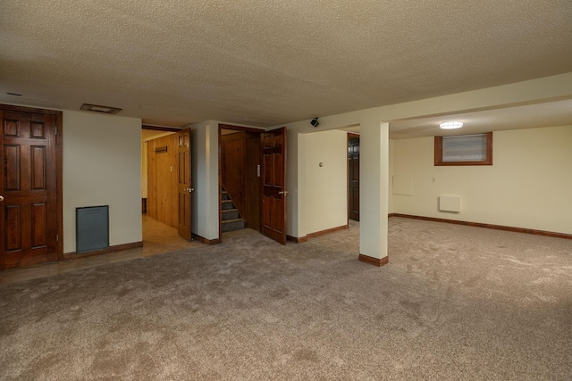 finished basement featuring carpet flooring, baseboards, a textured ceiling, and stairs