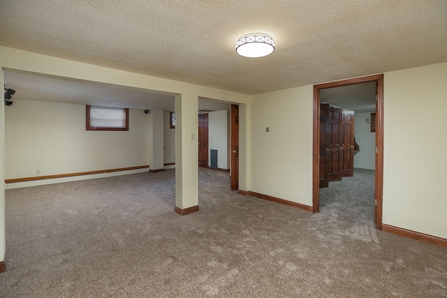 finished below grade area with baseboards, carpet, and a textured ceiling