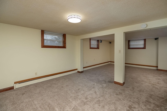 below grade area with a textured ceiling, a baseboard heating unit, and carpet