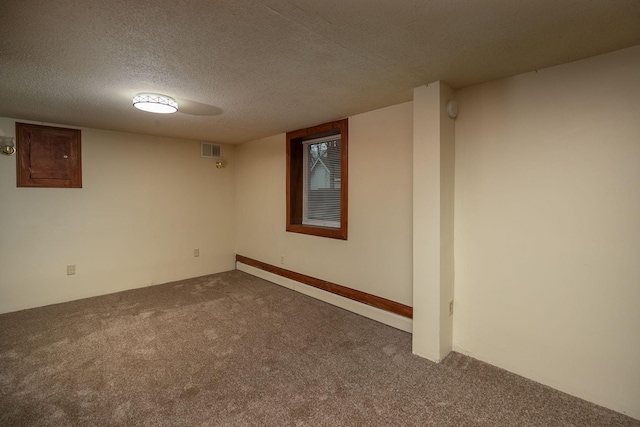 finished below grade area featuring visible vents, carpet floors, and a textured ceiling