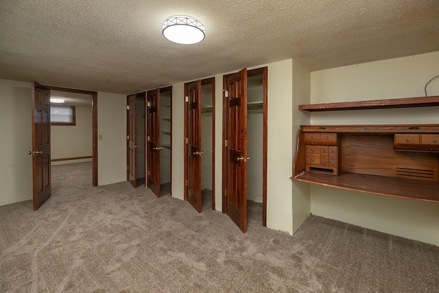 below grade area with a baseboard heating unit, a textured ceiling, and carpet flooring