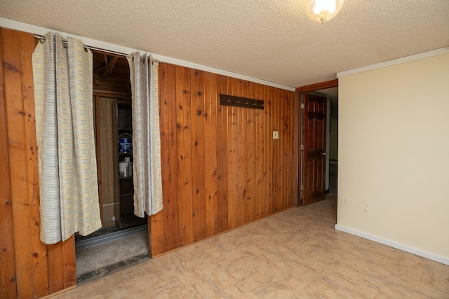 unfurnished room with tile patterned floors, wooden walls, and a textured ceiling