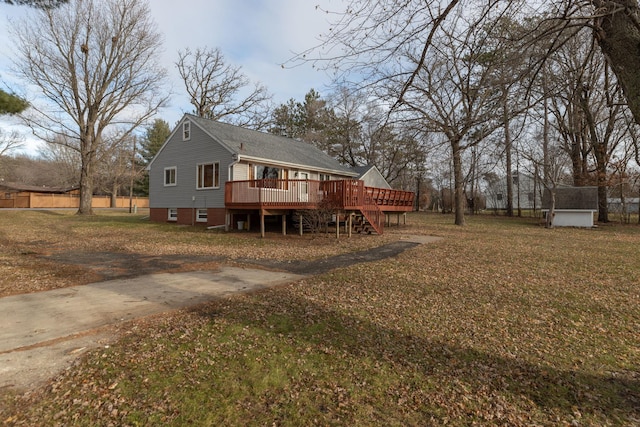 rear view of house with a wooden deck, a yard, and stairs