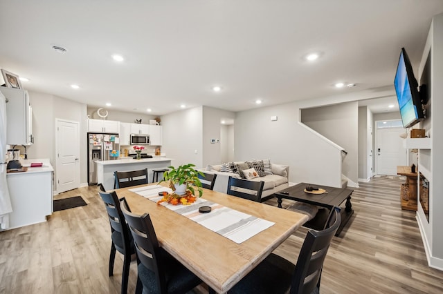 dining area with recessed lighting, light wood-type flooring, and stairs