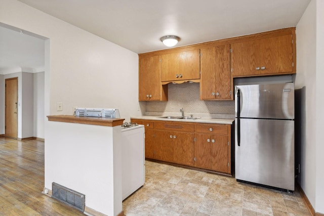 kitchen with visible vents, brown cabinetry, and freestanding refrigerator