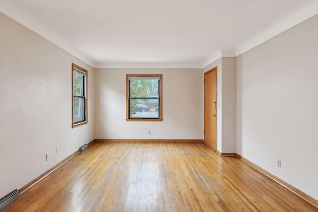 unfurnished room with a baseboard heating unit, baseboards, and light wood finished floors