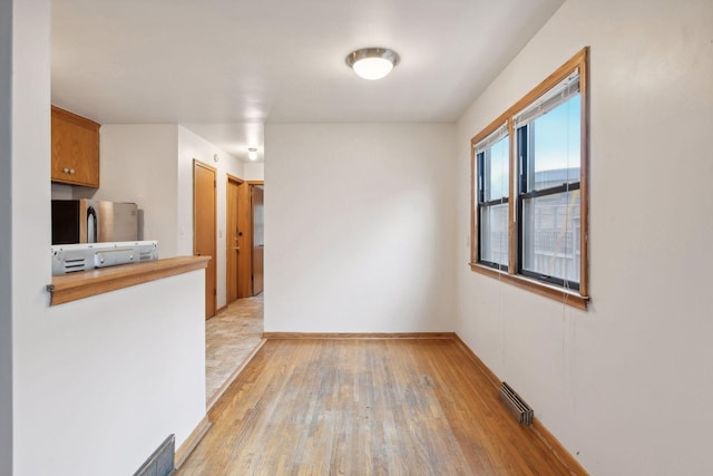 empty room with visible vents, light wood-style flooring, and baseboards