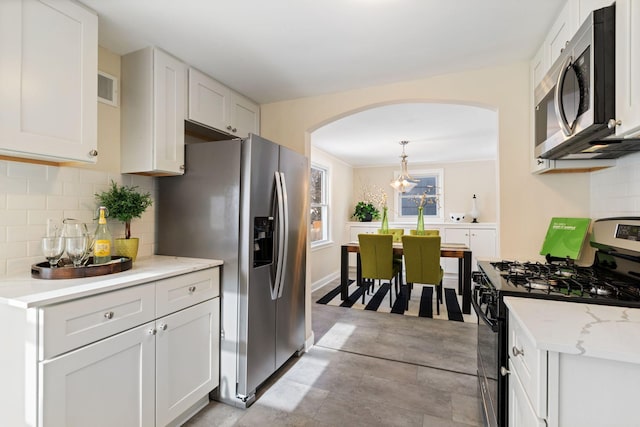 kitchen with arched walkways, visible vents, white cabinets, appliances with stainless steel finishes, and decorative backsplash