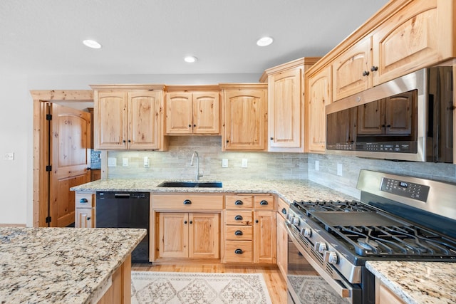 kitchen featuring light stone counters, light wood-style flooring, stainless steel appliances, a sink, and light brown cabinetry