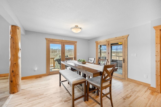 dining space with light wood-type flooring, french doors, a textured ceiling, and baseboards