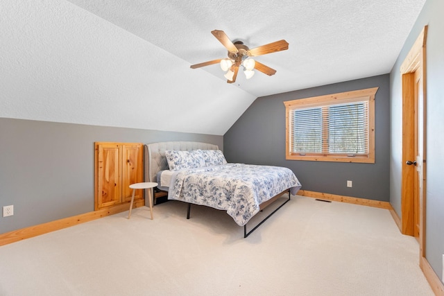 bedroom featuring visible vents, baseboards, lofted ceiling, ceiling fan, and a textured ceiling