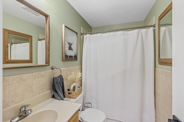 bathroom with tile walls, visible vents, vanity, and toilet