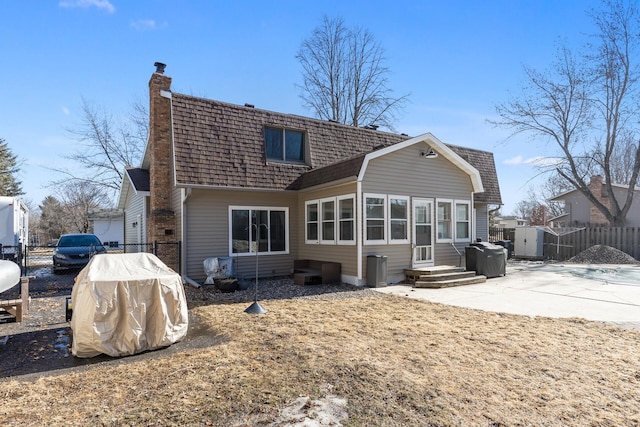 rear view of property with entry steps, a chimney, fence, and a patio