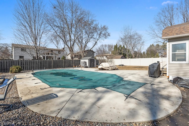 view of pool featuring a fenced in pool, a fenced backyard, a patio, and a storage shed