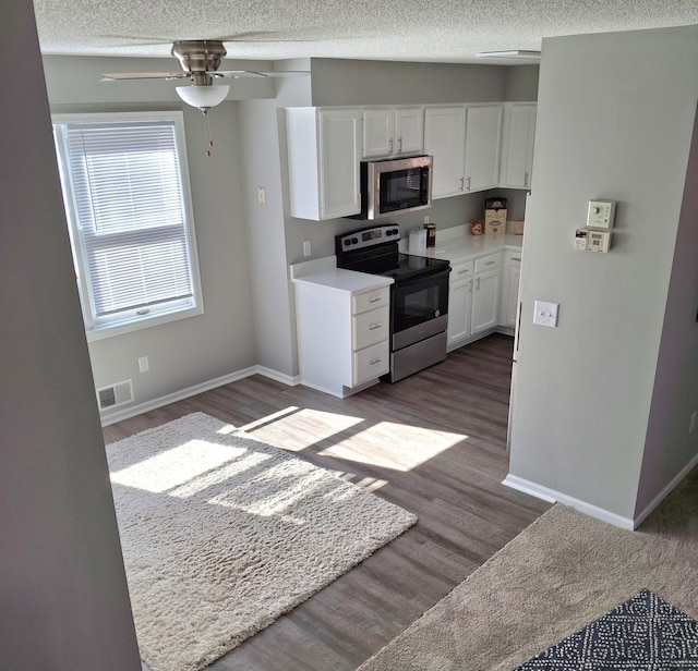 kitchen with visible vents, a textured ceiling, white cabinetry, and electric stove