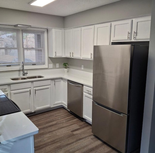 kitchen featuring dark wood finished floors, light countertops, stainless steel appliances, white cabinetry, and a sink