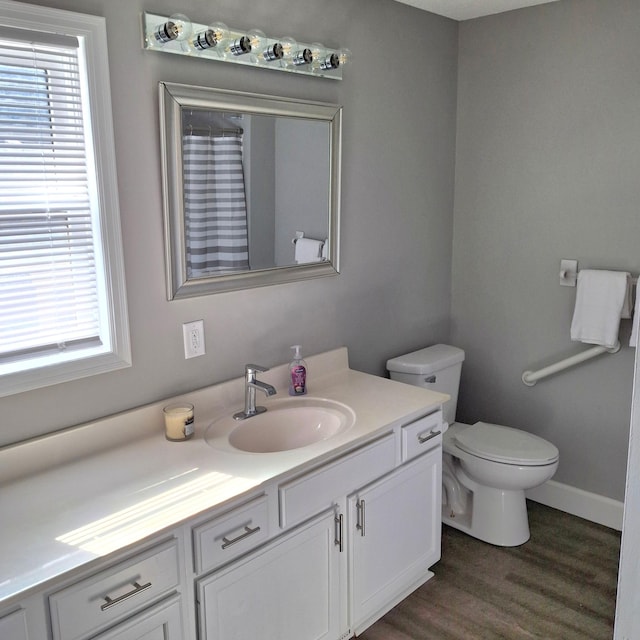 bathroom with curtained shower, baseboards, toilet, wood finished floors, and vanity